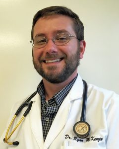 A photo of a man smiling. He is a Veterinarian, wearing a stethoscope. 